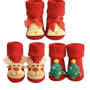Peut inclure: Chaussettes rouges pour bébés sur le thème de Noël. Les chaussettes présentent divers motifs, notamment des cloches avec des nœuds rouges, des visages de rennes et des sapins de Noël verts avec des étoiles jaunes. Idéal pour les fêtes.