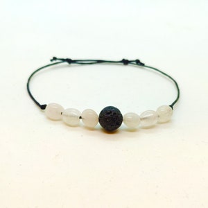 May include: A black lava rock bead bracelet with white oval beads and a black cord.