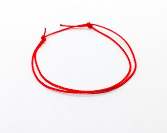 May include: A red string bracelet with a simple knot design.