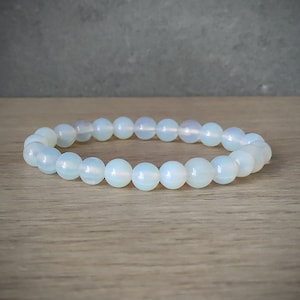 Peut inclure: Un bracelet en perles d'opale blanche avec un design simple. Le bracelet est composé de perles rondes et lisses et est parfait pour un usage quotidien.