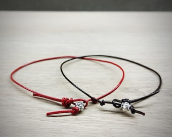 May include: Two leather cord bracelets with silver bead accents. One bracelet is red and the other is black.
