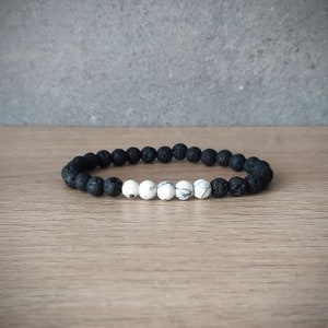 Könnte beinhalten: Ein Armband aus schwarzen Lava- und weißen Howlith-Perlen. Das Armband besteht aus kleinen, runden Perlen.