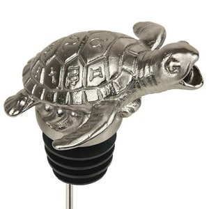 May include: Silver-toned bottle stopper shaped like a sea turtle with a black rubber stopper and a metal rod. The turtle has a detailed shell with raised markings.