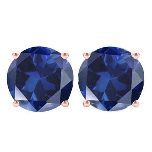 May include: A pair of round blue gemstone stud earrings set in rose gold.
