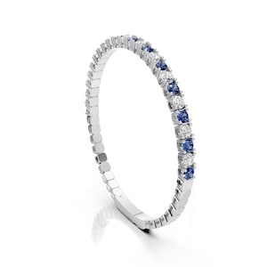 May include: A silver bracelet with alternating blue and clear gemstones. The gemstones are round and set in a continuous line around the bracelet. The bracelet is on a white background.