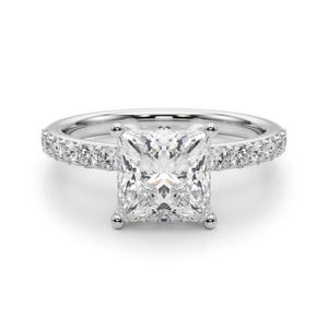 May include: A dazzling engagement ring featuring a large, square-cut diamond as the centerpiece. The band is crafted from polished white metal and is embellished with smaller, sparkling stones along the sides, creating a halo effect around the main diamond.