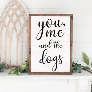May include: A white wooden sign with black calligraphy that reads "you, me and the dogs".