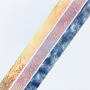 May include: Three rolls of washi tape with a firework design. The tape is in shades of blue, pink, and orange.