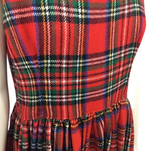 May include: Red plaid dress with a gathered skirt. The dress has a sleeveless design and a classic plaid pattern.
