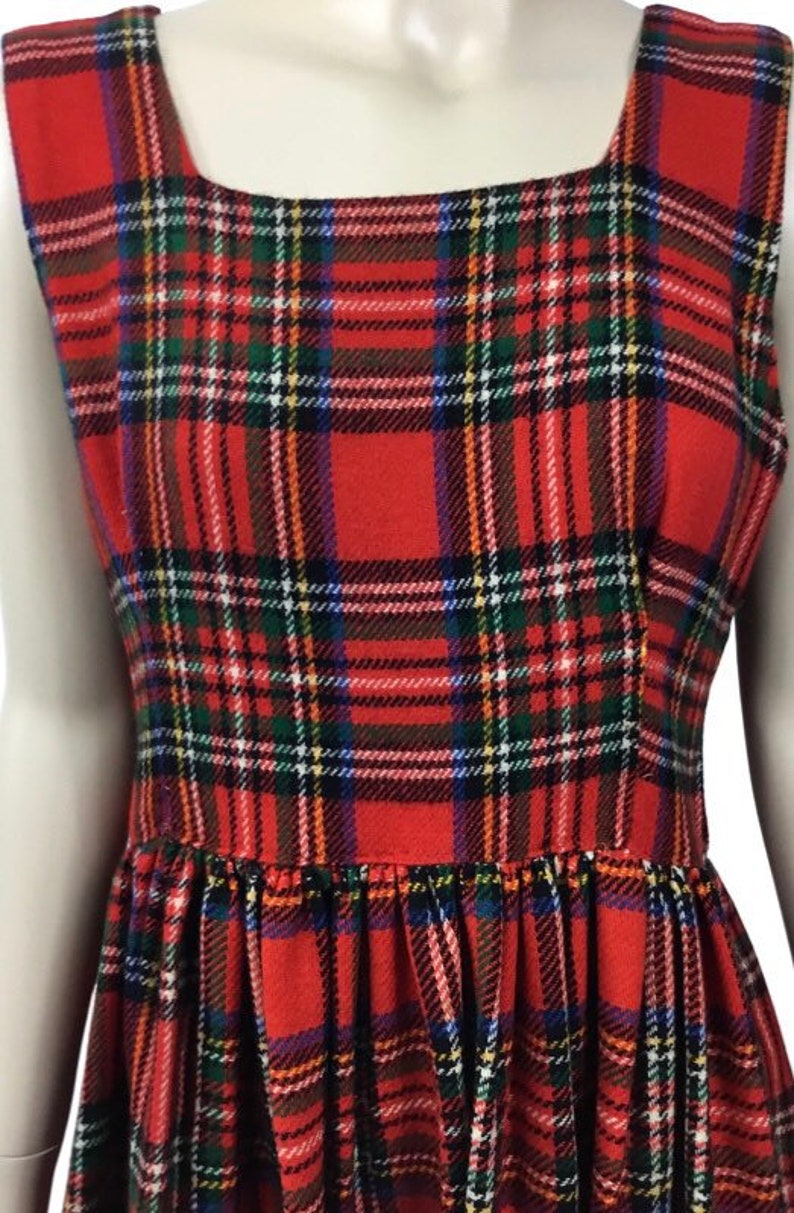 May include: A red plaid sleeveless dress with a square neckline. The dress has a gathered skirt and is made of a soft, comfortable fabric.