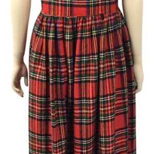 May include: A red, green, and blue plaid sleeveless dress with a square neckline. The dress has a gathered skirt and falls to the ankles.