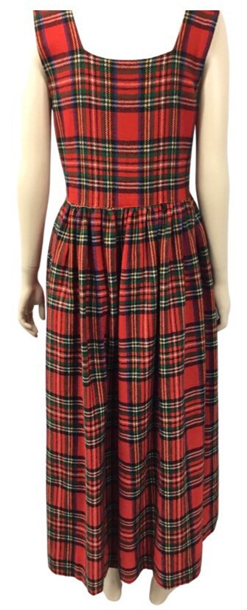 May include: A red, green, and blue plaid sleeveless dress with a square neckline. The dress has a gathered skirt and falls to the ankles.
