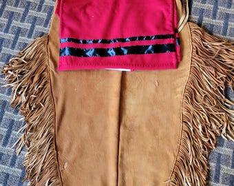 Puede incluir: Un par de polainas de cuero marrón con flecos y una manta de silla de fieltro rojo con ribete de cinta negra.
