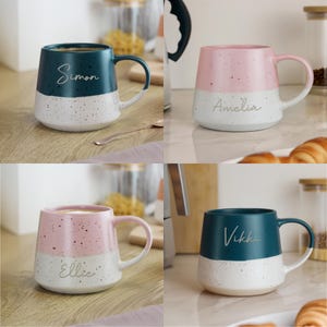 May include: Four ceramic mugs with a speckled design. Each mug is two-toned, with a coloured top half and a white bottom half. The mugs are teal, pink, and white. Each mug has a name written on it: Simon, Amelia, Ellie, and Vikki.