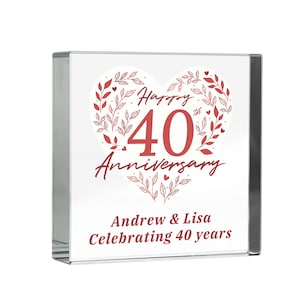 May include: A clear glass block with a white background. It features a red heart-shaped design with the words "Happy 40th Anniversary". The names "Andrew & Lisa" and the phrase "Celebrating 40 years" are also displayed.