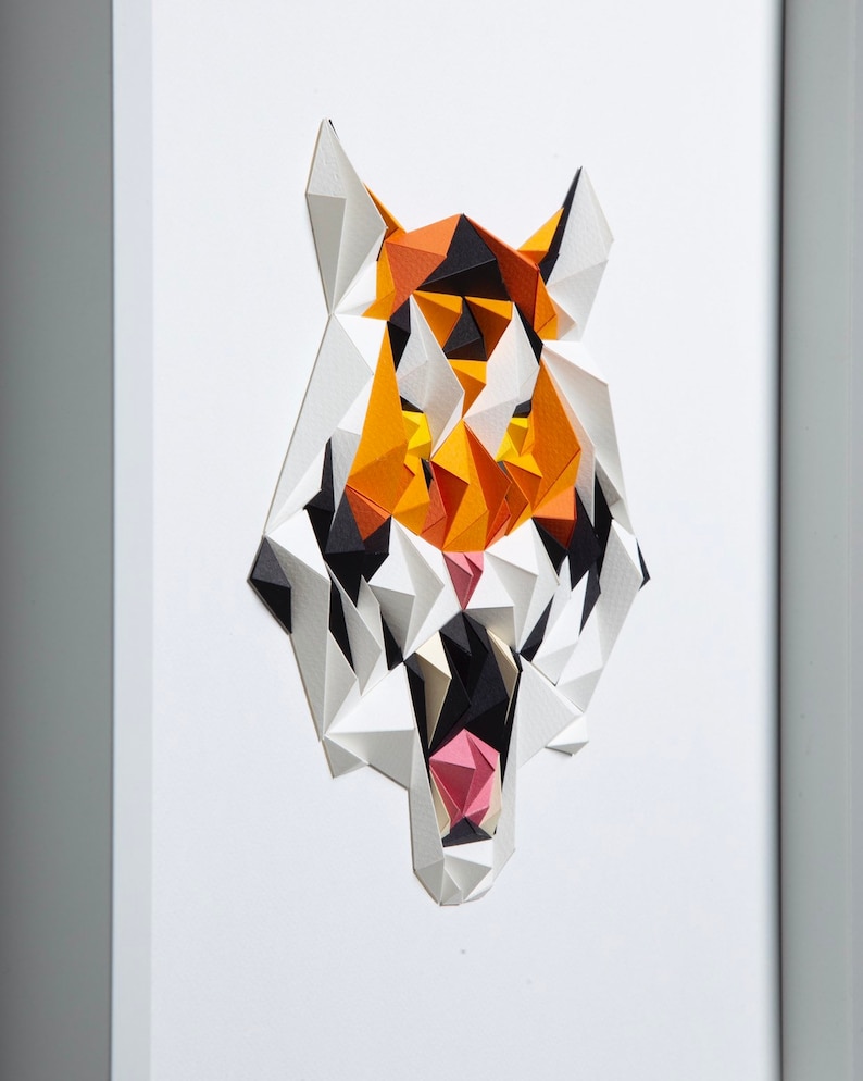 Puede incluir: Una escultura de cabeza de tigre de papel con un dise&ntilde;o geom&eacute;trico. El tigre es naranja, negro y blanco con una boca rosa.