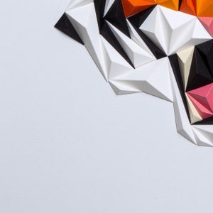 Puede incluir: Arte de pared geom&eacute;trico abstracto hecho de papel en tonos de blanco, negro, naranja, rosa y beige. El papel est&aacute; doblado en tri&aacute;ngulos y dispuesto en un patr&oacute;n.
