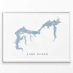 Può includere: Una stampa ad acquerello del lago Ocoee, un lago nel Tennessee, con uno schema di colori blu chiaro. La stampa è incorniciata in una cornice bianca.