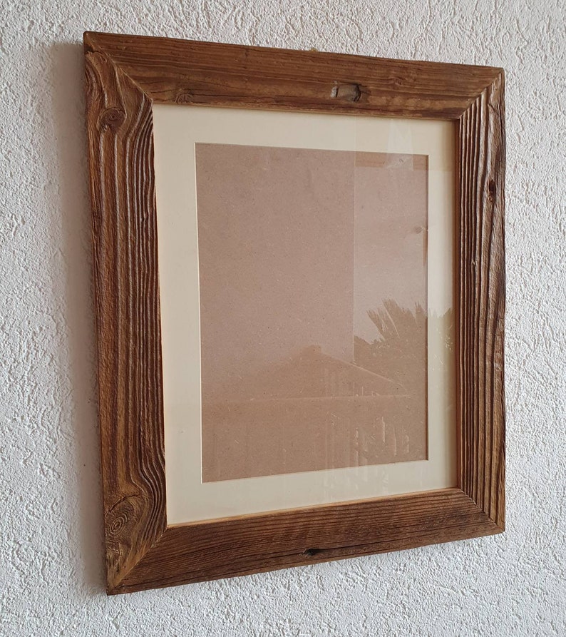 May include: A rustic wooden picture frame with a natural brown finish. The frame has a thick, textured border and a simple, rectangular shape.