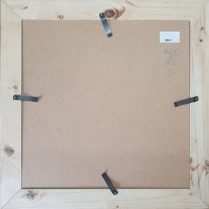 May include: The back of a wooden picture frame with four metal hanging clips. The frame has a brown paper backing with the number "B641" written on it.