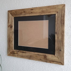 Puede incluir: Un marco de fotos de madera r&uacute;stica con un passe-partout negro y un inserto de cart&oacute;n marr&oacute;n. El marco tiene un acabado de madera natural y est&aacute; hecho de madera reciclada.