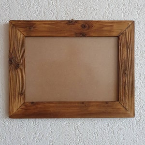 May include: A rustic wooden picture frame with a brown cardboard backing. The frame has a natural wood finish and a simple design.