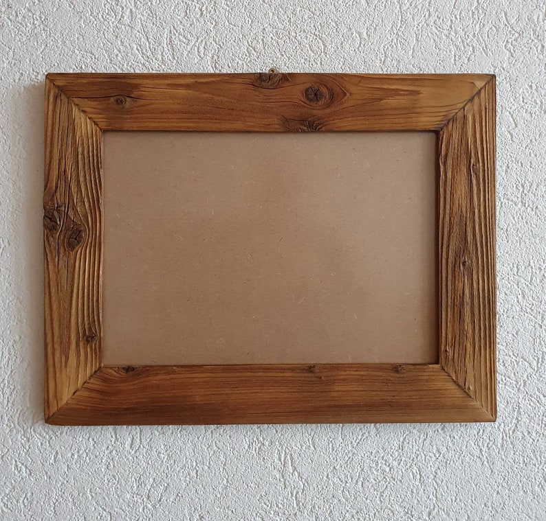 May include: A rustic wooden picture frame with a brown cardboard backing. The frame has a natural wood finish and a simple design.