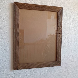 May include: A rustic wooden picture frame with a brown finish. The frame has a simple design with a rectangular shape and a slightly distressed look.