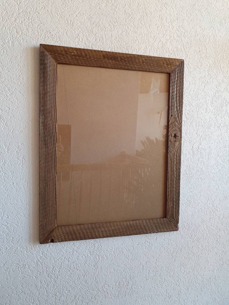 May include: A rustic wooden picture frame with a brown finish. The frame has a simple design with a rectangular shape and a slightly distressed look.