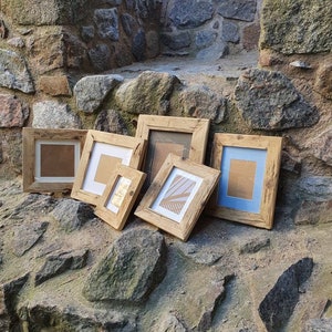 Puede incluir: Seis marcos de fotos de madera r&uacute;stica de diferentes tama&ntilde;os, dispuestos sobre una superficie de piedra. Los marcos son todos de madera natural con un aspecto tosco y sin terminar. Algunos marcos tienen un acabado marr&oacute;n claro, mientras que otros tienen un acabado marr&oacute;n oscuro. Los marcos est&aacute;n todos vac&iacute;os y listos para ser rellenados con fotos u obras de arte.