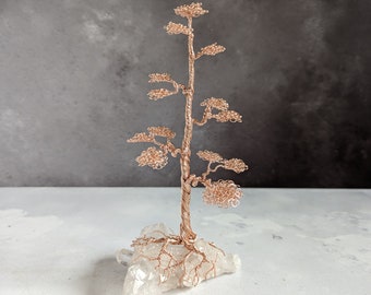 Rose gold coloured copper wire tree on a quartz base