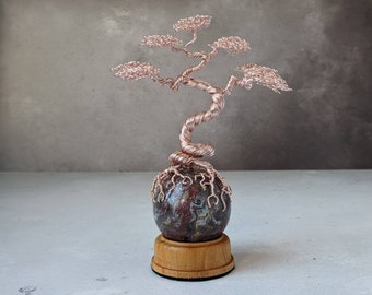Rose gold coloured copper wire tree sculpture on a palm root sphere with a natural wooden sphere holder