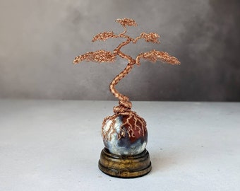 Copper wire tree on a carnelian sphere with a glossy dark wooden sphere holder