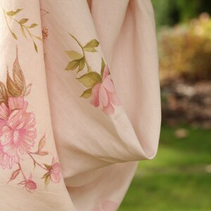May include: A pale pink linen scarf with a floral print featuring pink roses and green leaves.