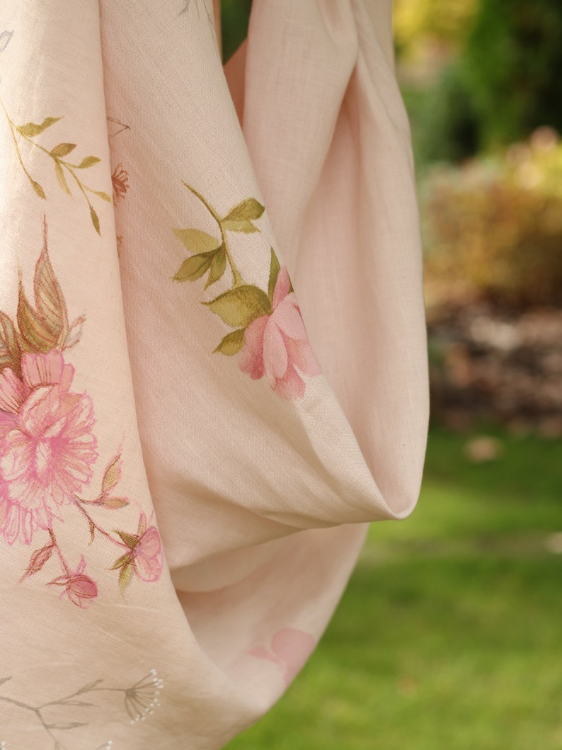 May include: A pale pink linen scarf with a floral print featuring pink roses and green leaves.