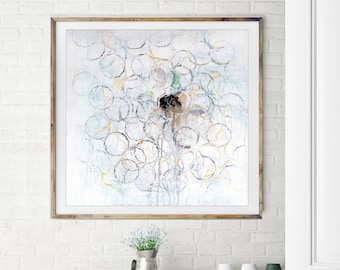 May include: A framed abstract painting with a white background and a design of overlapping circles in shades of gray, blue, and green. The circles are outlined in black and some have a light yellow tint. The painting is hanging on a white brick wall above a green cabinet and a black table with a white chair.