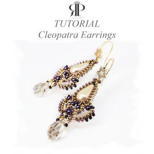 May include: Cleopatra earrings with a teardrop design. The earrings feature a pearlescent centre, surrounded by gold and purple beads. A clear crystal hangs from the bottom, and a star-shaped accent adorns the top. The word "TUTORIAL" is visible.