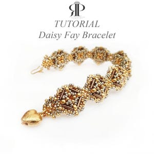 Op de afbeelding: Een kralenarmband met een herhalend ruitpatroon in metallic goud- en zilvertinten, voorzien van een goudkleurige hartvormige bedel aan het ene uiteinde en een metalen sluiting aan het andere. De tekst "TUTORIAL Daisy Fay Bracelet" staat boven het sieraad.