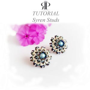 Puede incluir: Un par de pendientes de botón con cuentas, con una cuenta central azul metálico rodeada por capas de cuentas de semillas color crema, plateadas y azul oscuro en un patrón floral. El texto TUTORIAL Syren Studs aparece arriba.