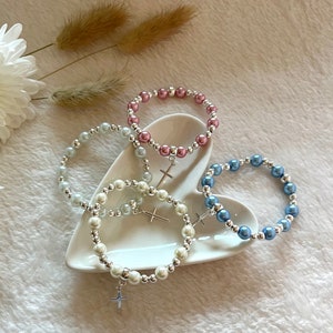 4 Choices of bracelet colours sit in a heart shaped trinket dish.  The colours are white, ivory, blue and antique pink.  The background is textured beige with pampas grass and white flower styling.