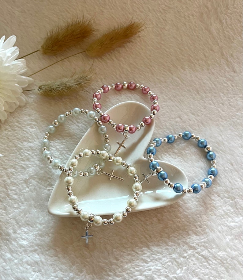 4 Choices of bracelet colours sit in a heart shaped trinket dish.  The colours are white, ivory, blue and antique pink.  The background is textured beige with pampas grass and white flower styling.