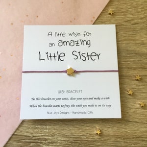 May include: A white card with a purple string tied around it with a gold star charm. The card reads "A little wish for an amazing Little Sister" and "WISH BRACELET" with instructions on how to use the bracelet. The card also says "Blue Jays Designs - Handmade Gifts".