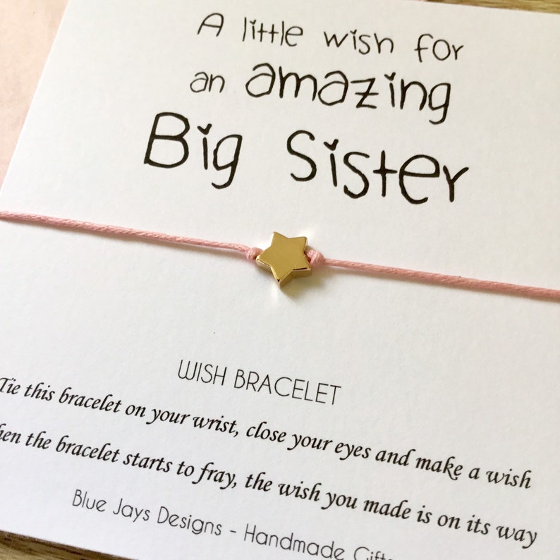 May include: A pink wish bracelet with a gold star charm and a card that reads "A little wish for an amazing Big Sister". Tie this bracelet on your wrist, close your eyes and make a wish. When the bracelet starts to fray, the wish you made is on its way. Blue Jays Designs - Handmade Gifts"