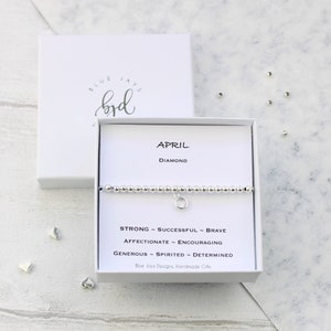 May include: A silver bracelet with a charm that says "April" and "Diamond". The bracelet is in a white box with the words "Blue Jays Designs, Handmade Gifts".