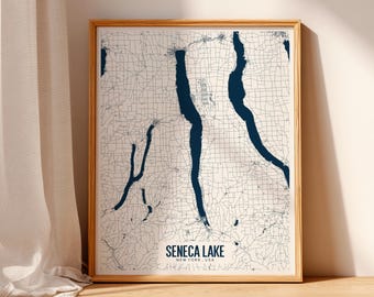 May include: A framed map print of Seneca Lake, New York, USA. The map features a detailed outline of the lake in dark blue against a light background, with a network of roads and towns. The frame is made of light-colored wood.