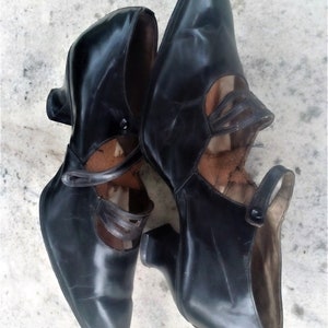 May include: A pair of black leather heeled shoes with a strap detail and a pointed toe.