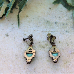 Peut inclure: Une paire de boucles d'oreilles vintage &agrave; clip. Chaque boucle d'oreille pr&eacute;sente un cadre d&eacute;coratif en m&eacute;tal de couleur laiton avec un centre en pierre de couleur turquoise. Les boucles d'oreilles ont un design orn&eacute; et un m&eacute;canisme &agrave; clip &agrave; vis.