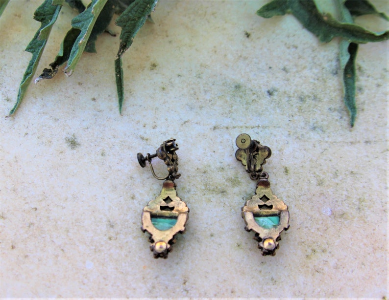 Peut inclure: Une paire de boucles d'oreilles vintage &agrave; clip. Chaque boucle d'oreille pr&eacute;sente un cadre d&eacute;coratif en m&eacute;tal de couleur laiton avec un centre en pierre de couleur turquoise. Les boucles d'oreilles ont un design orn&eacute; et un m&eacute;canisme &agrave; clip &agrave; vis.