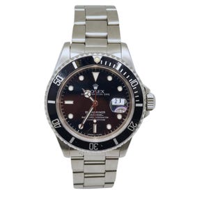 May include: A stainless steel wristwatch with a black dial, a rotating black bezel with white numerals, and a metal link bracelet. The watch face features the Rolex logo, luminous hour markers, a date window with a magnifier, and silver hands.