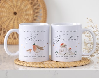 May include: Two white ceramic mugs with the text "First Christmas as my Nanna" and "First Christmas as my Grandad". Each mug features a bird illustration and the text "Lots of Love, Isla XX 2025" and "Lots of Love, Ava XX 2025".